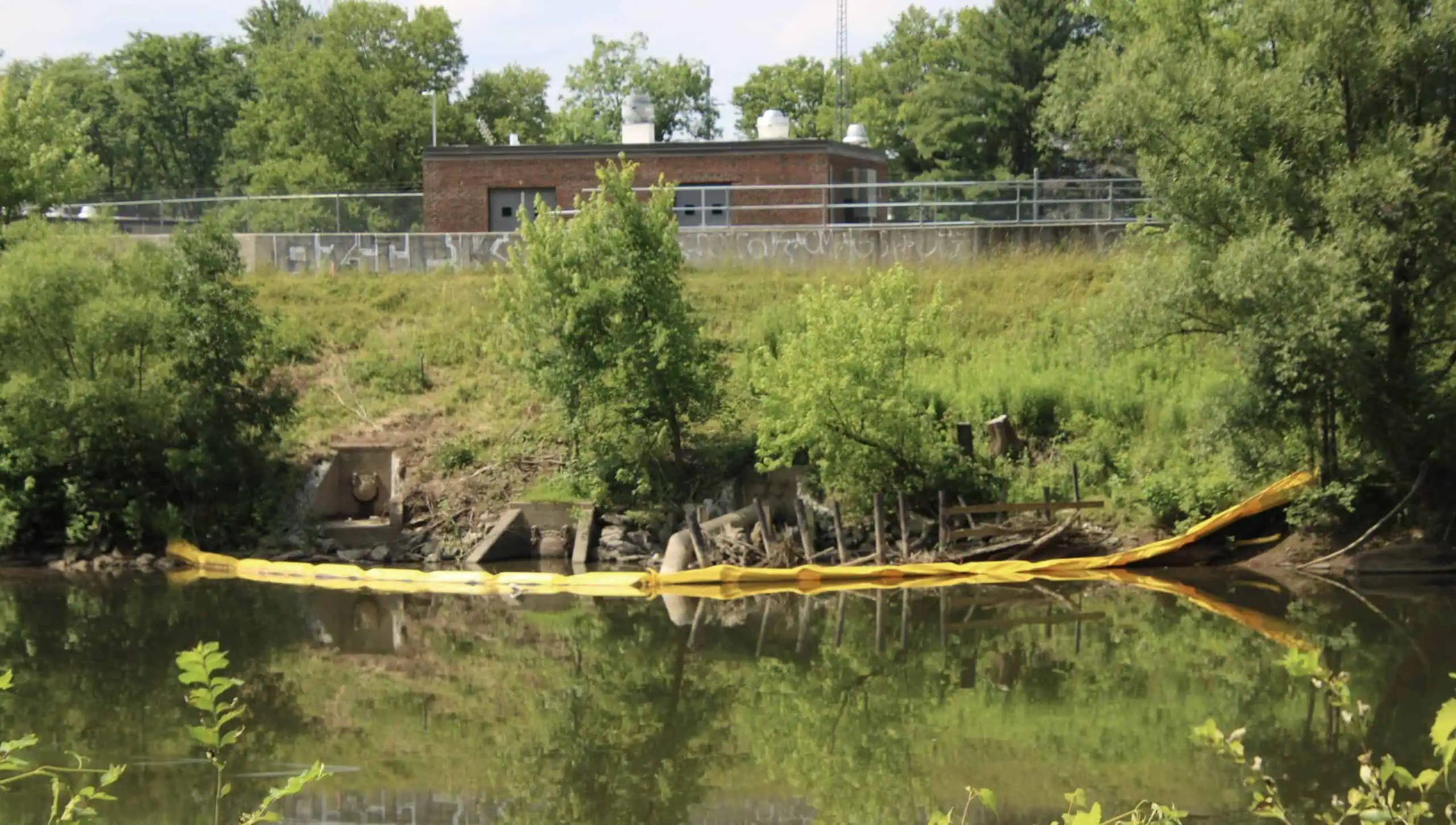 (Rick Miller/Olean Star) Yellow inflatable tubing is visible in the Allegheny River near the Olean wastewater treatment plant as part of a state project to fortify the flood control dikes near the treatment plant. A crane has also been moved to outside the plant to help move equipment around the dike.