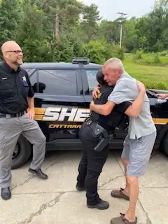 (Photo provided) Stan Cizdziel of West Valley, who was in anaphylactic shock after getting stung repeatedly by bees on July 26 while cutting trees hugs Cattaraugus County Sheriff's Deputy Rachel Zimmer last week, thanking her for rushing to the scene with an Epi-pen that brought him out of shock. At left is Sheriff Eric Butler.