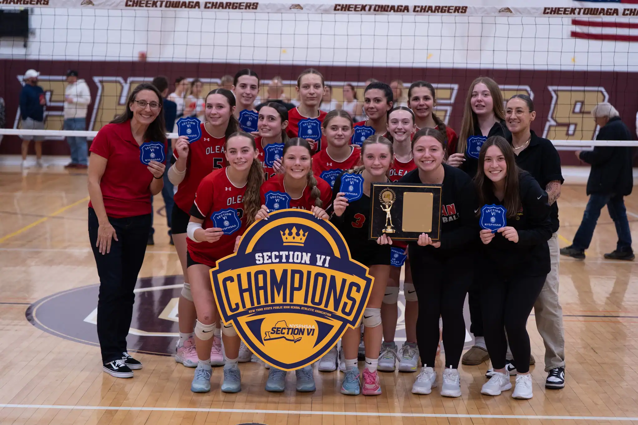 The Olean volleyball team poses with their Section VI championship patch and plaque after defeating Depew in three sets. | Photo by Hunter O. Lyle